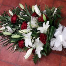 Beautiful Red Rose and White Lily Sheaf. Various foliage including Palm, Leatherleaf, Aspidistra finished of with a large crisp white bow.