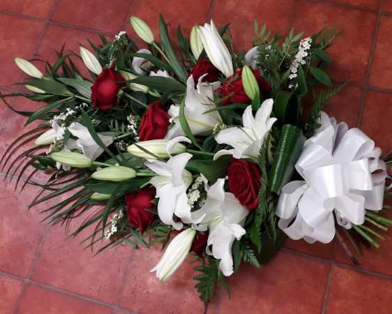Beautiful Red Rose and White Lily Sheaf. Various foliage including Palm, Leatherleaf, Aspidistra finished of with a large crisp white bow.
