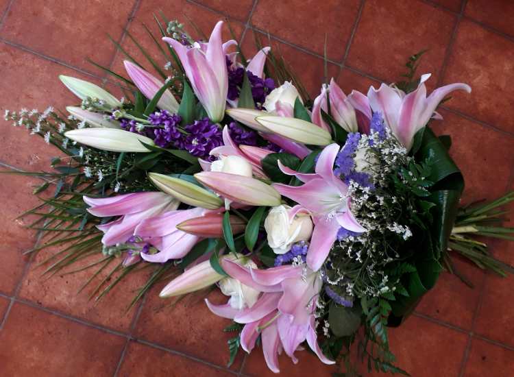 This tied sheaf is a pink and white theme with pink Lilies, large white Roses, blue Iris, Aster and complimentary foliage.