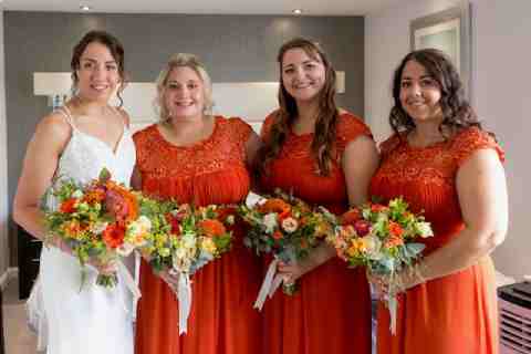 Jodie and James wedding, bridesmaids are wearing burnt orange matching dresses and the bouquets have a tropical theme.
