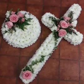 A beautiful mass based cross in white chrysanthemums with a pink ribbon trim and a central spray in pink Roses and white Freesia.